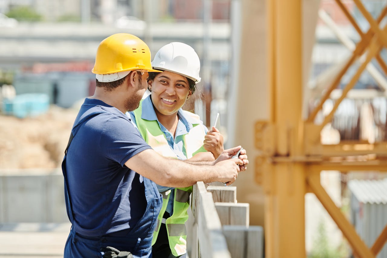 About Male and female construction workers discussing plans at a building site.